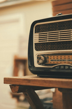 Close-up of a vintage radio on a wooden table, with a warm blurred background